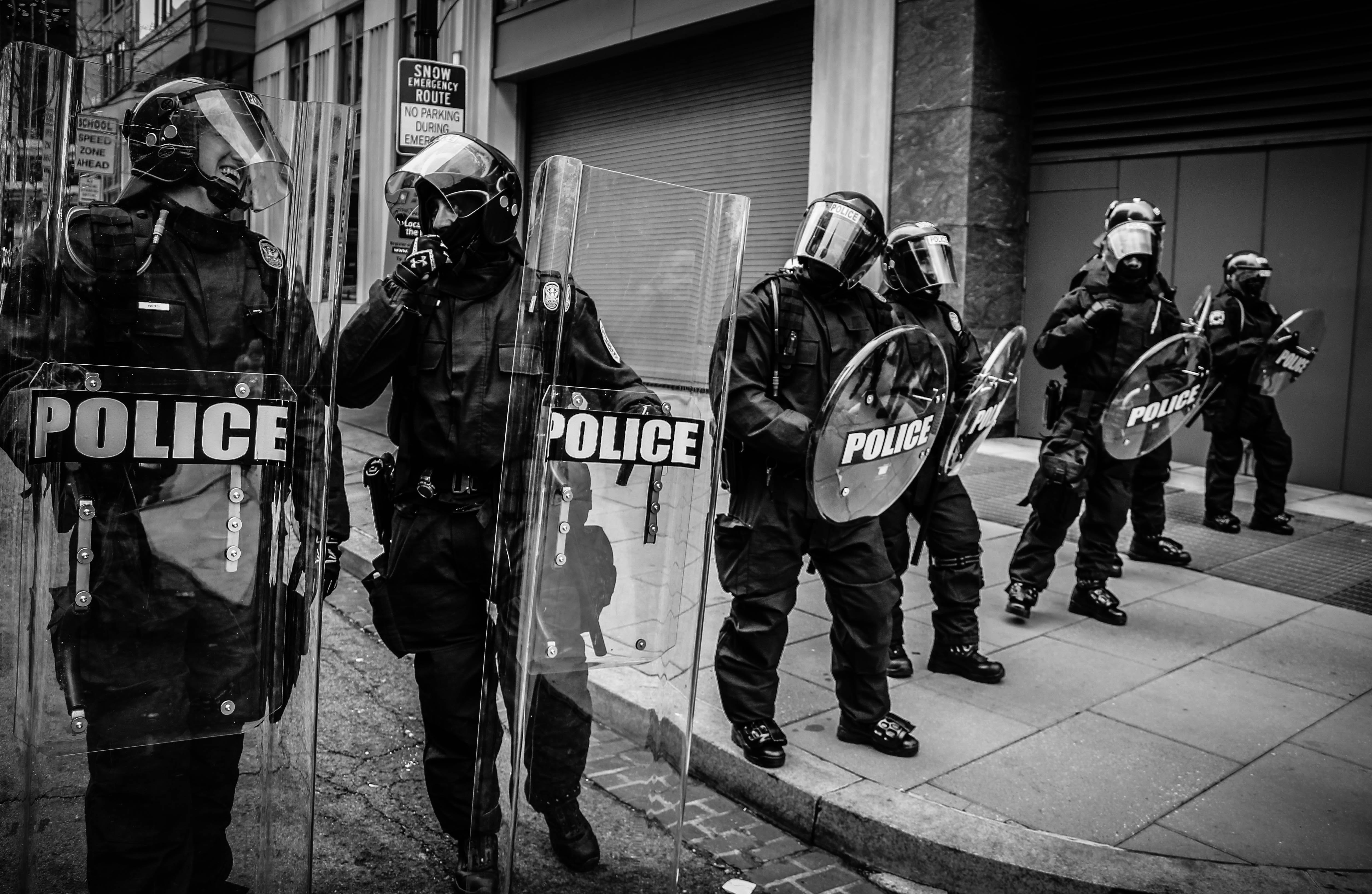 Police in riot gear; image by Spenser H, via Unsplash.com.