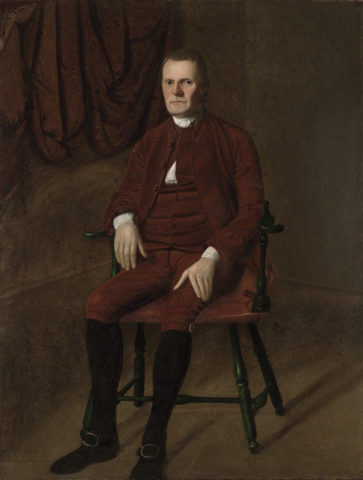 A portrait in dark brown tones, showing a stern-faced man on a simple wooden chair.