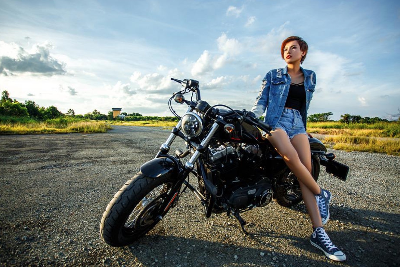 Woman in shorts leaning on motorcycle; image by Minh1857, via Pexels.com