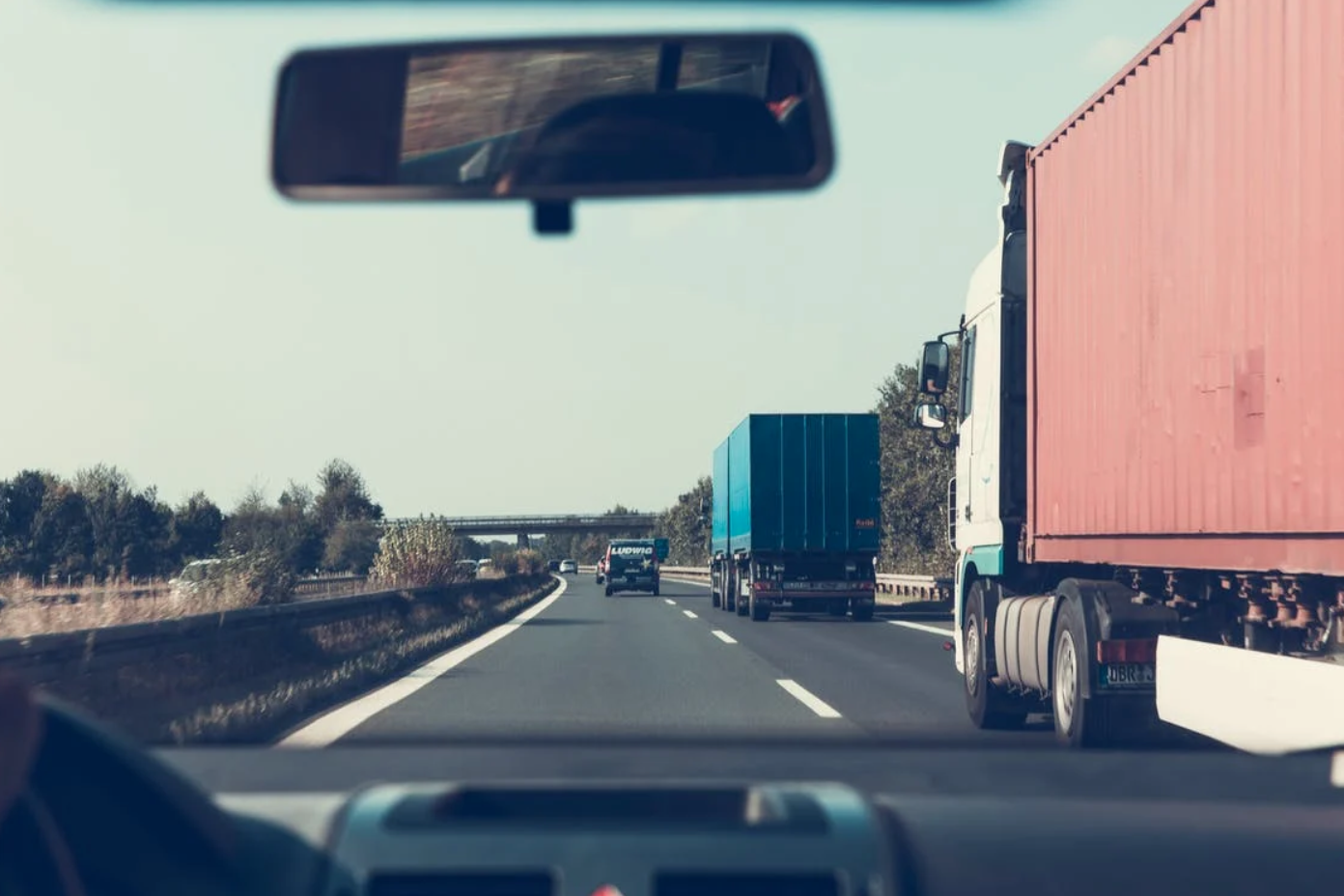 A blue and a red truck on the road; image by Markus Spiske, via Pexels.com.