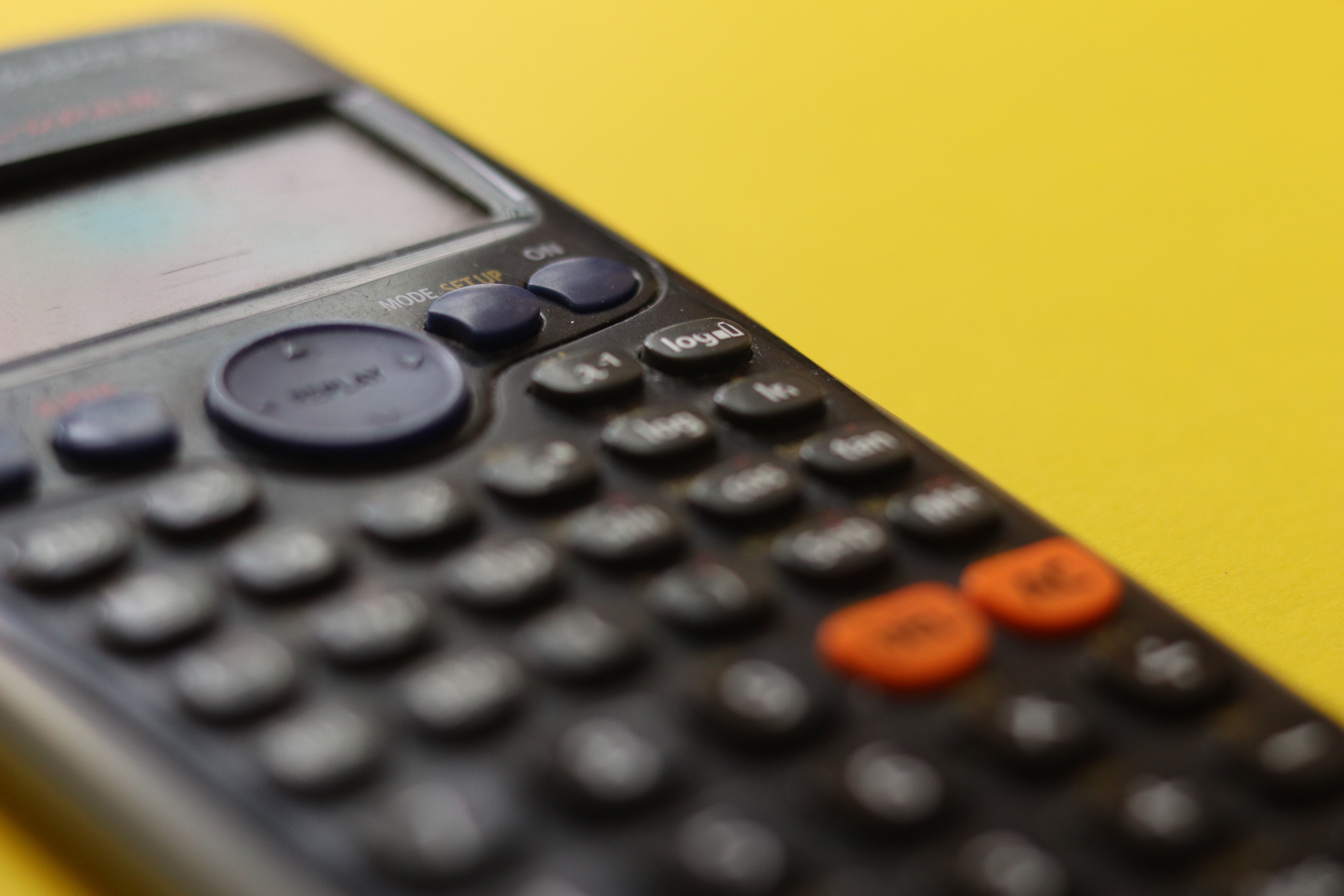 A calculator on a yellow background; image by Clayton Robbins, via Unsplash.com.