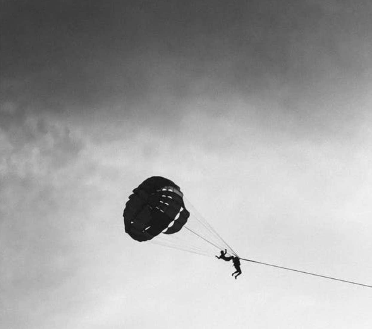 Parasailing in cloudy weather; image by Nitigya Soni, via Pexels.com.