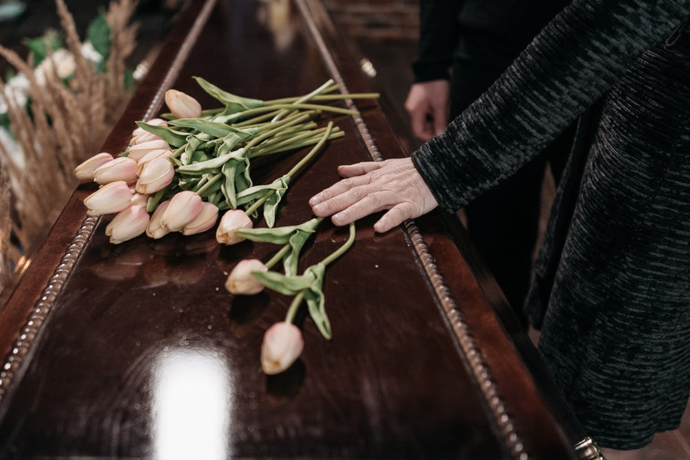 Person touching casket with roses on it; image by Pavel Danilyuk, via Unsplash.com.