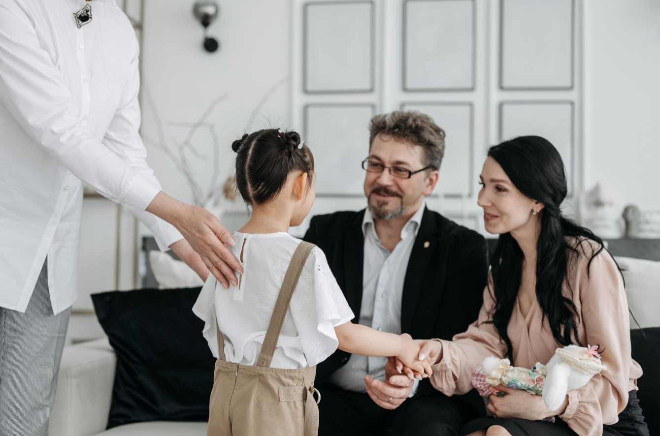 Seated couple greeting child; image via Imagesource.io.