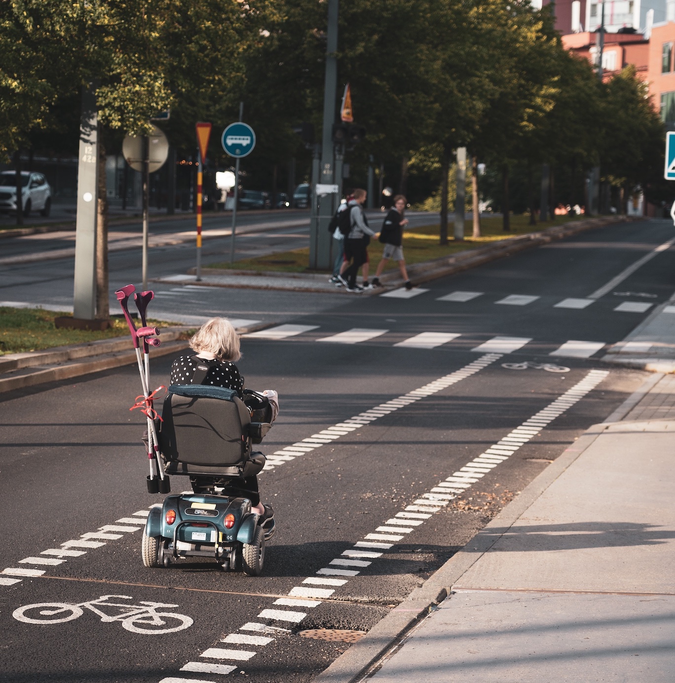 Woman using mobility scooter in bike lane; image by rasmus Gerdin, via Unsplash.com.