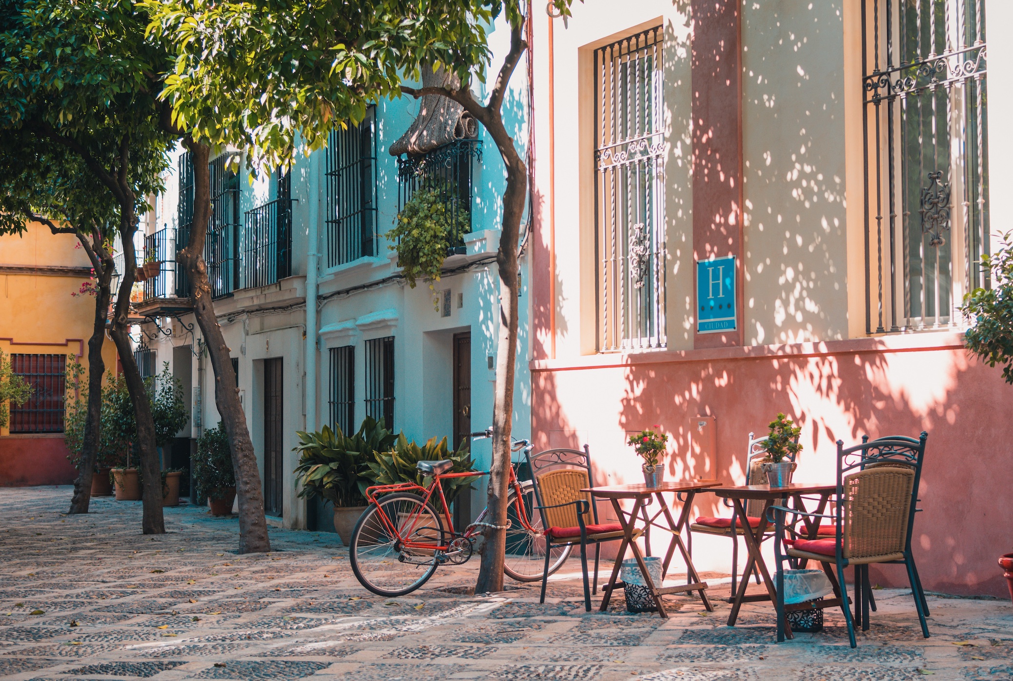 Bike parked by table at sidewalk cafe in Seville, Spain; image by Johan Mouchet, via Unsplash.com.