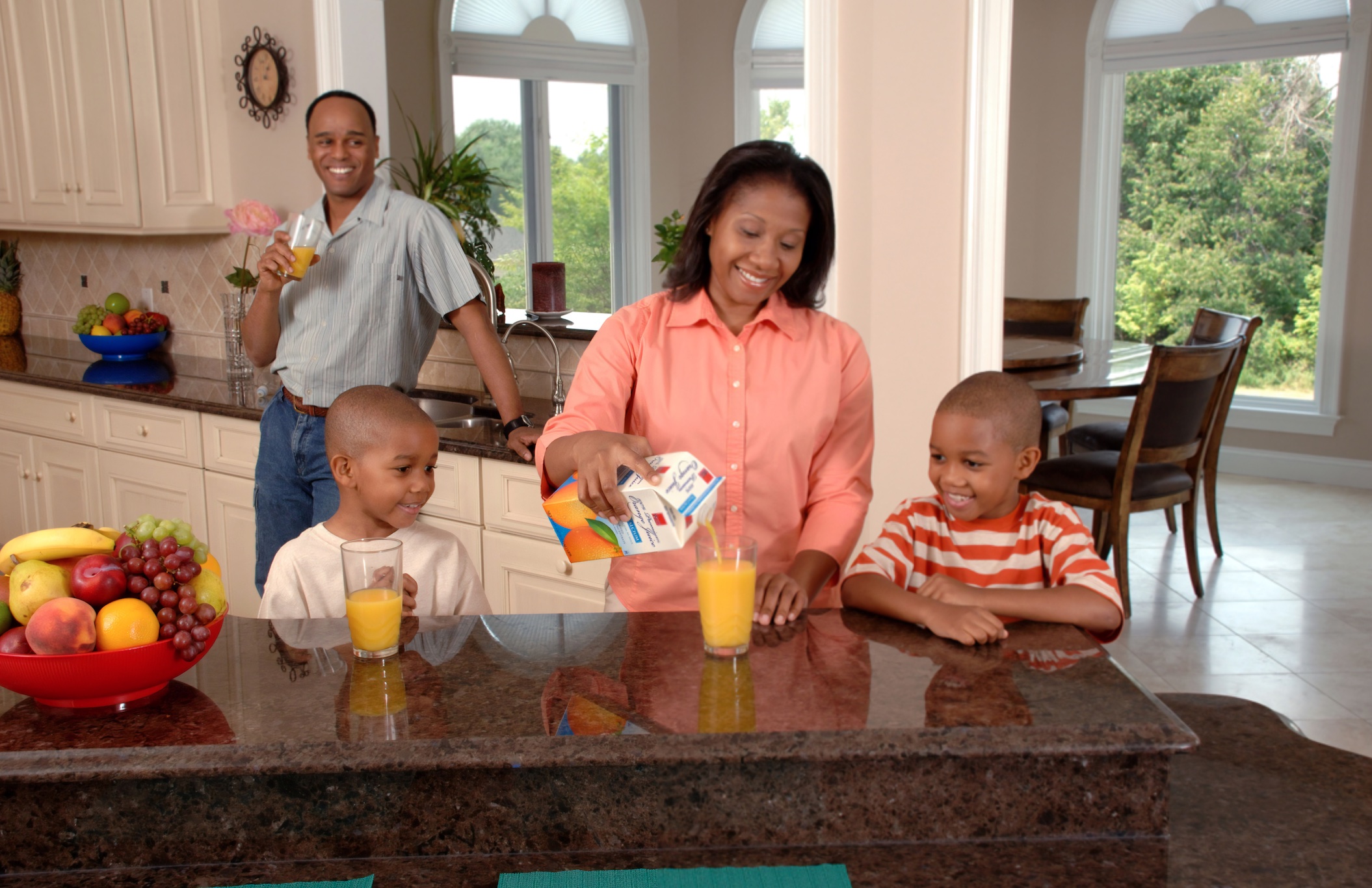 Black family in kitchen drinking orange juice; image by National Cancer Institute, via Unsplash.com.