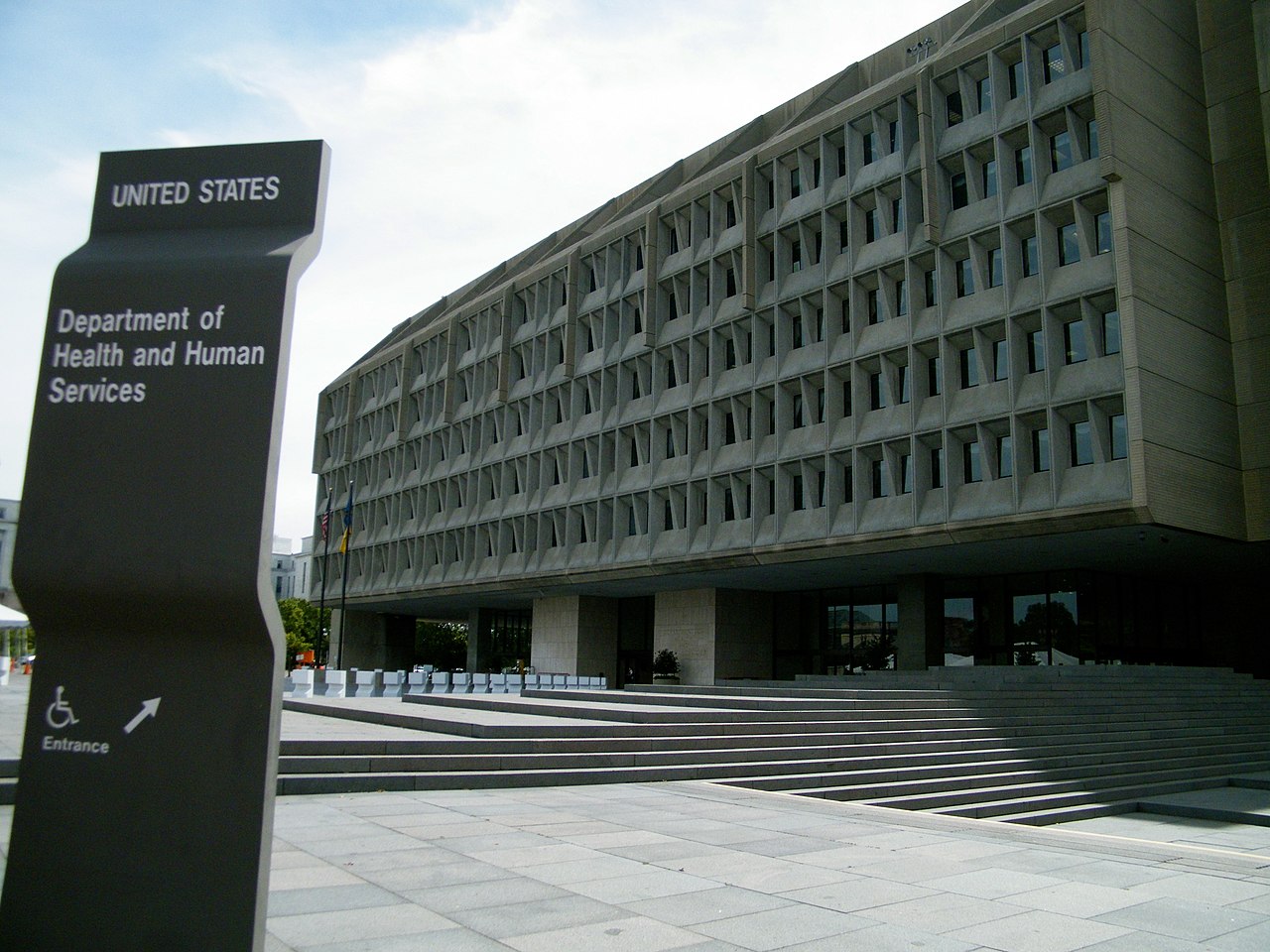A multi-story government building behind a sign that says "Department of Health and Human Services".