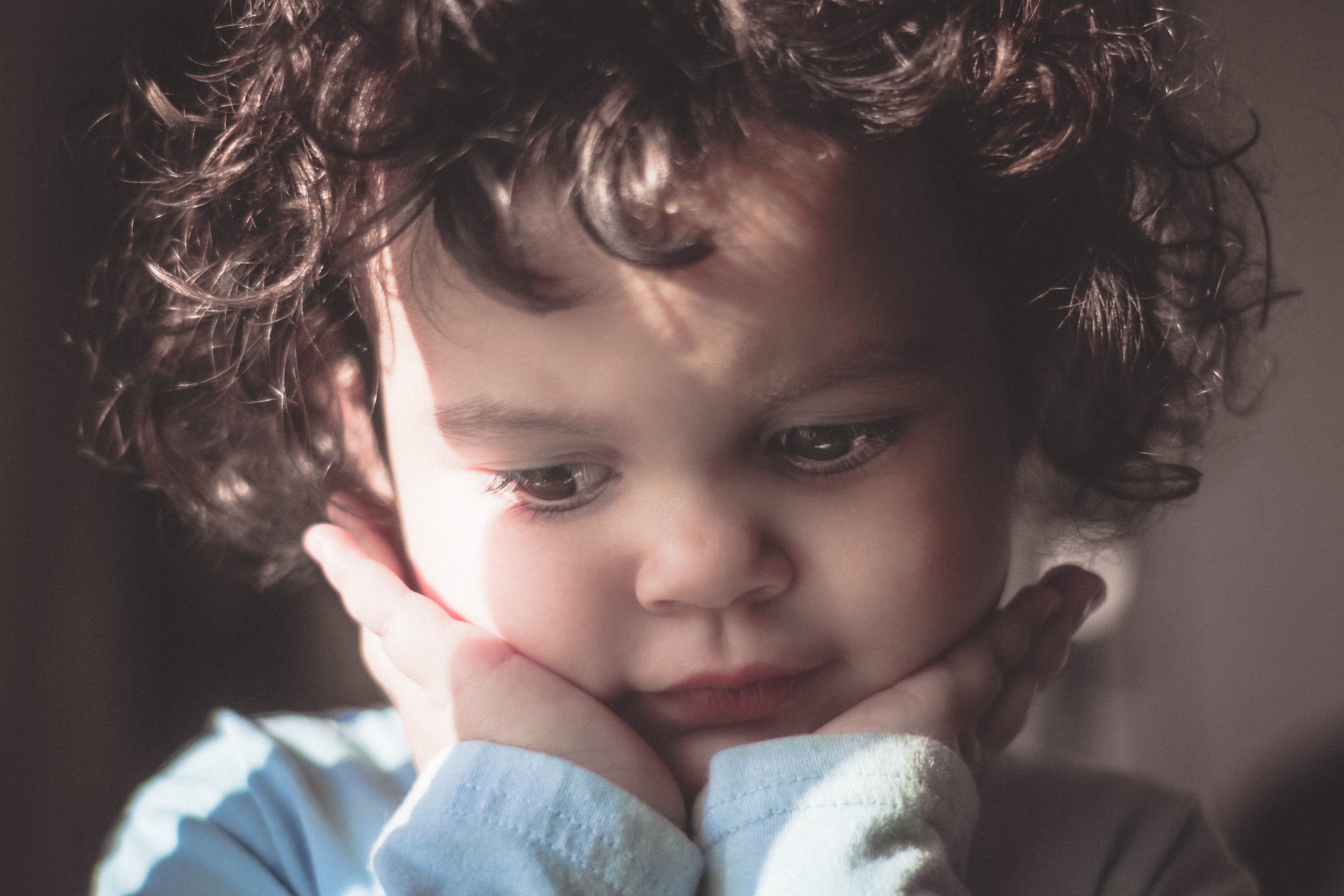 Toddler holding face looking thoughtful; image by Ricky Turner, via Unsplash.com.