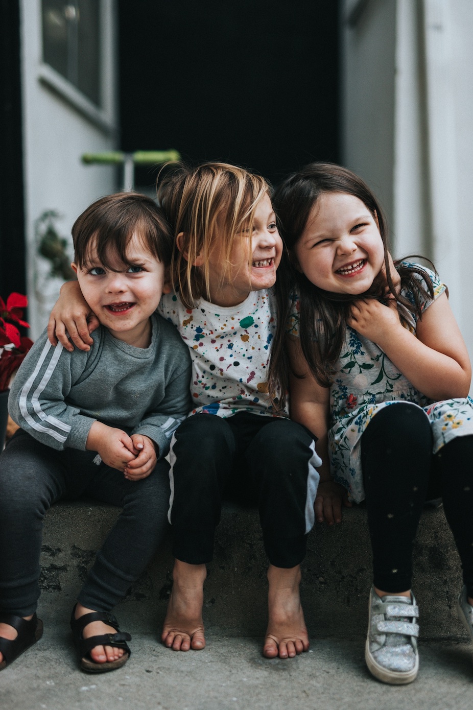 Two little girls and one little boy sitting on step; image by Nathan Dumlao, via Unsplash.com.
