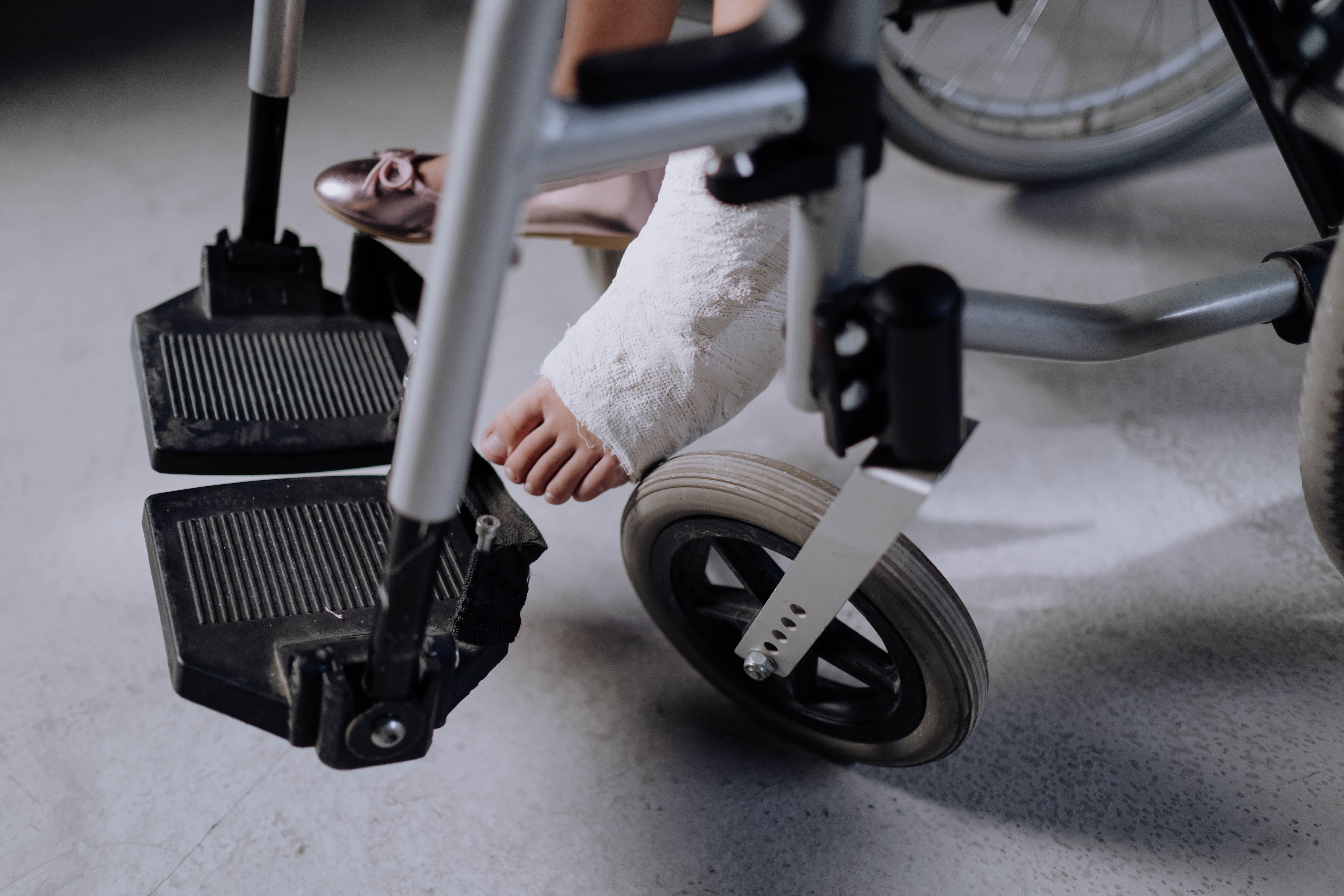Girl with cast in wheelchair; image by Cottonbro, via Pexels.com.