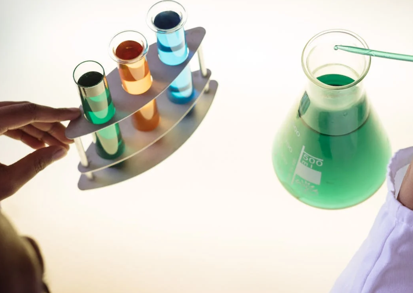 Lab technician examining interaction of chemicals; image by RF._.studio, via Pexels.com.