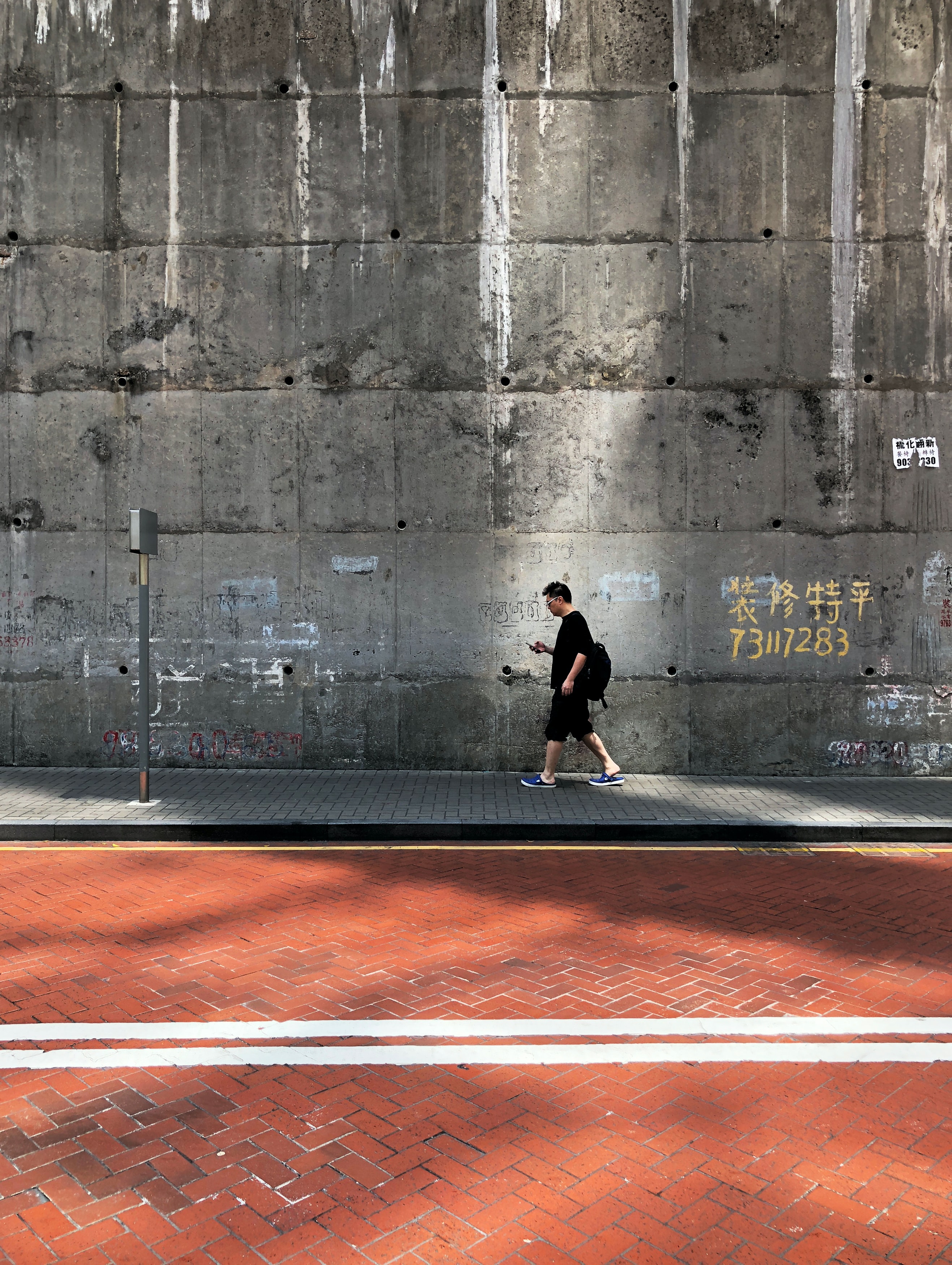 Man texting while walking; image by Pop and Zebra, via Unsplash.com.