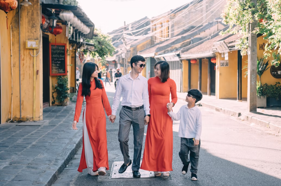Family walking down street holding hands; image by Hoi An Photographer, via Unsplash.com.