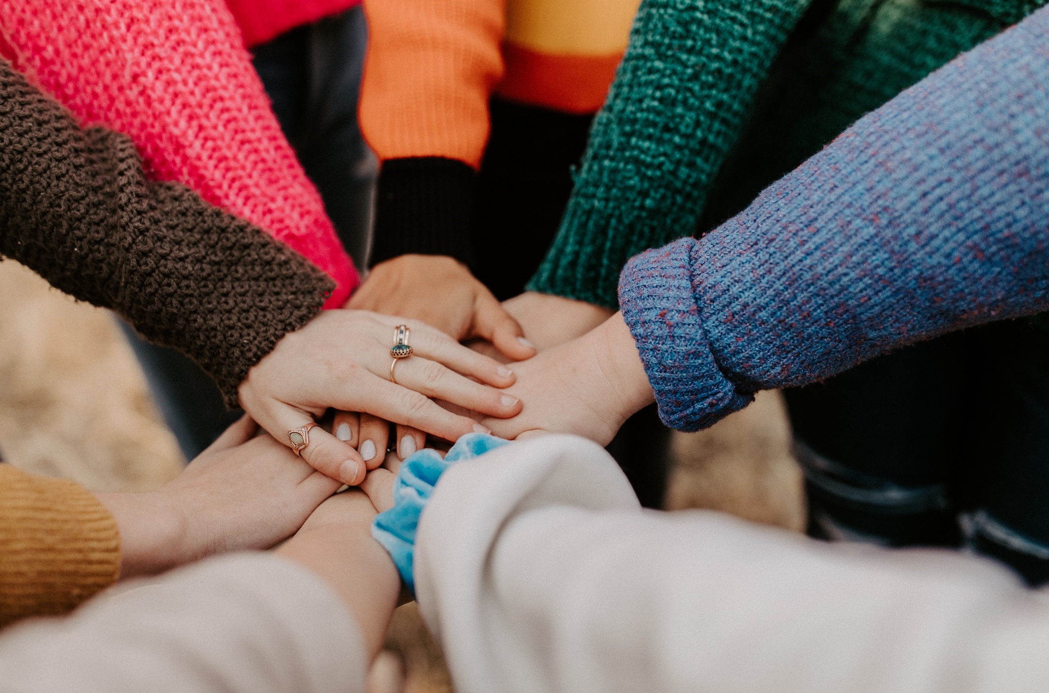 Group of women putting hands in a circle; image by Hannah Busing, via Unsplash.com.