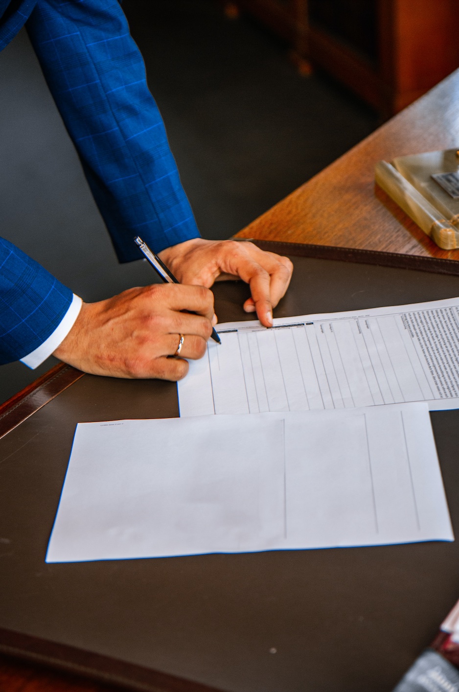 Man in blue suit signing papers; image by Leon Seibert, via Unsplash.com.