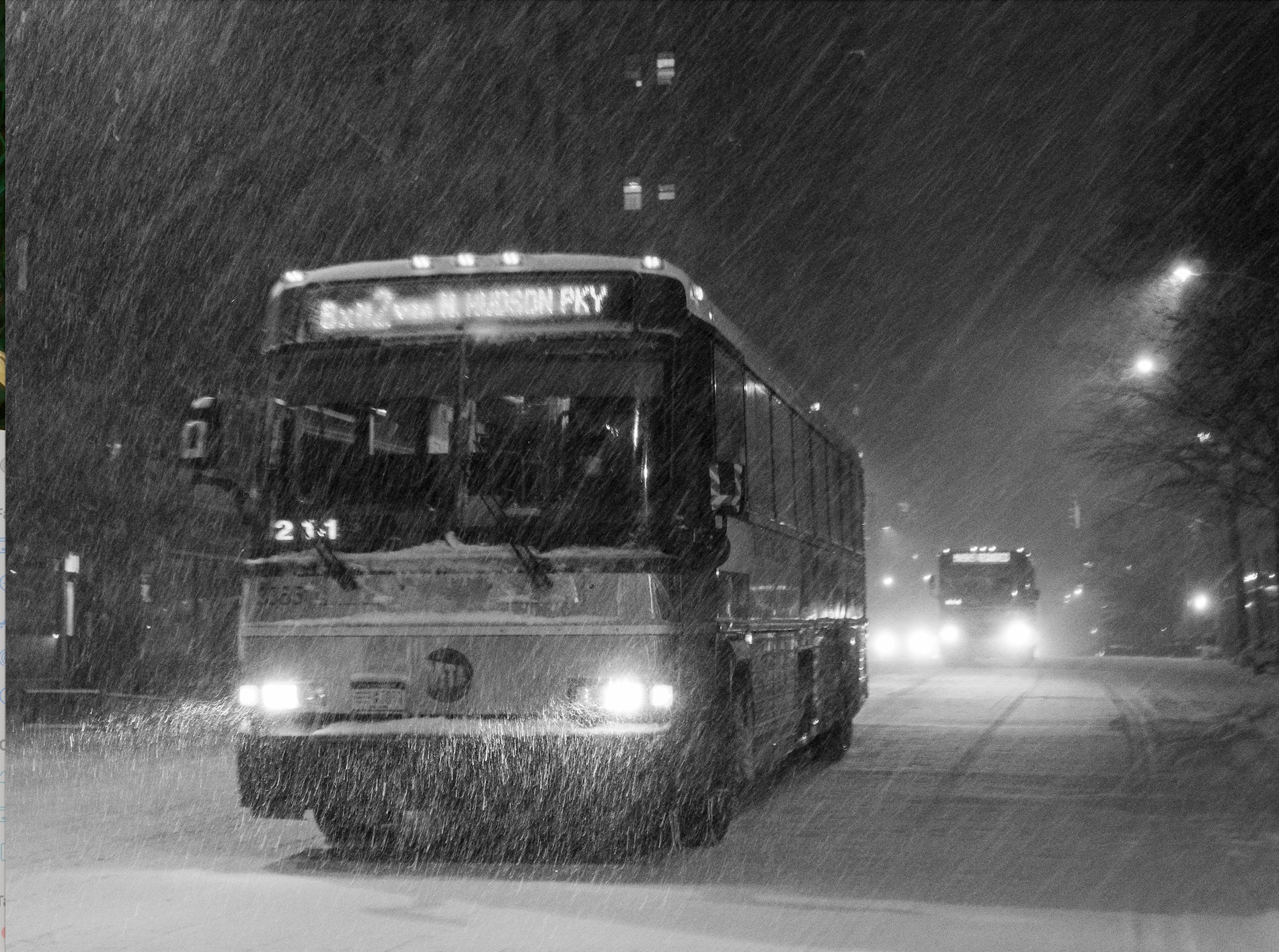 Black and white shot of bus driving in snow at night; image by Clay LeConey, via Unsplash.com.