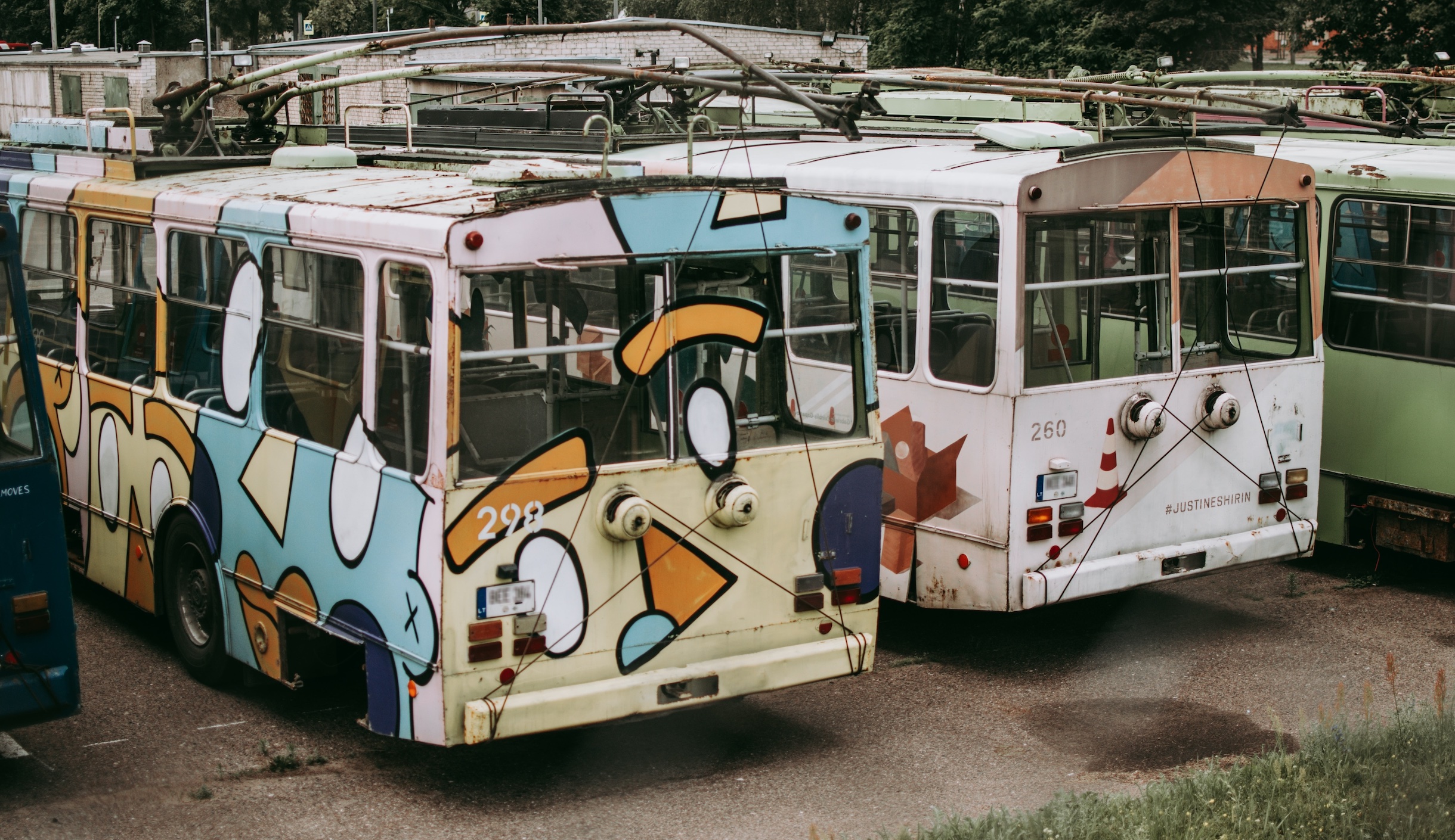Group of old, colorfully painted busses; image by Egidijus Bielskis, via Unsplash.com.