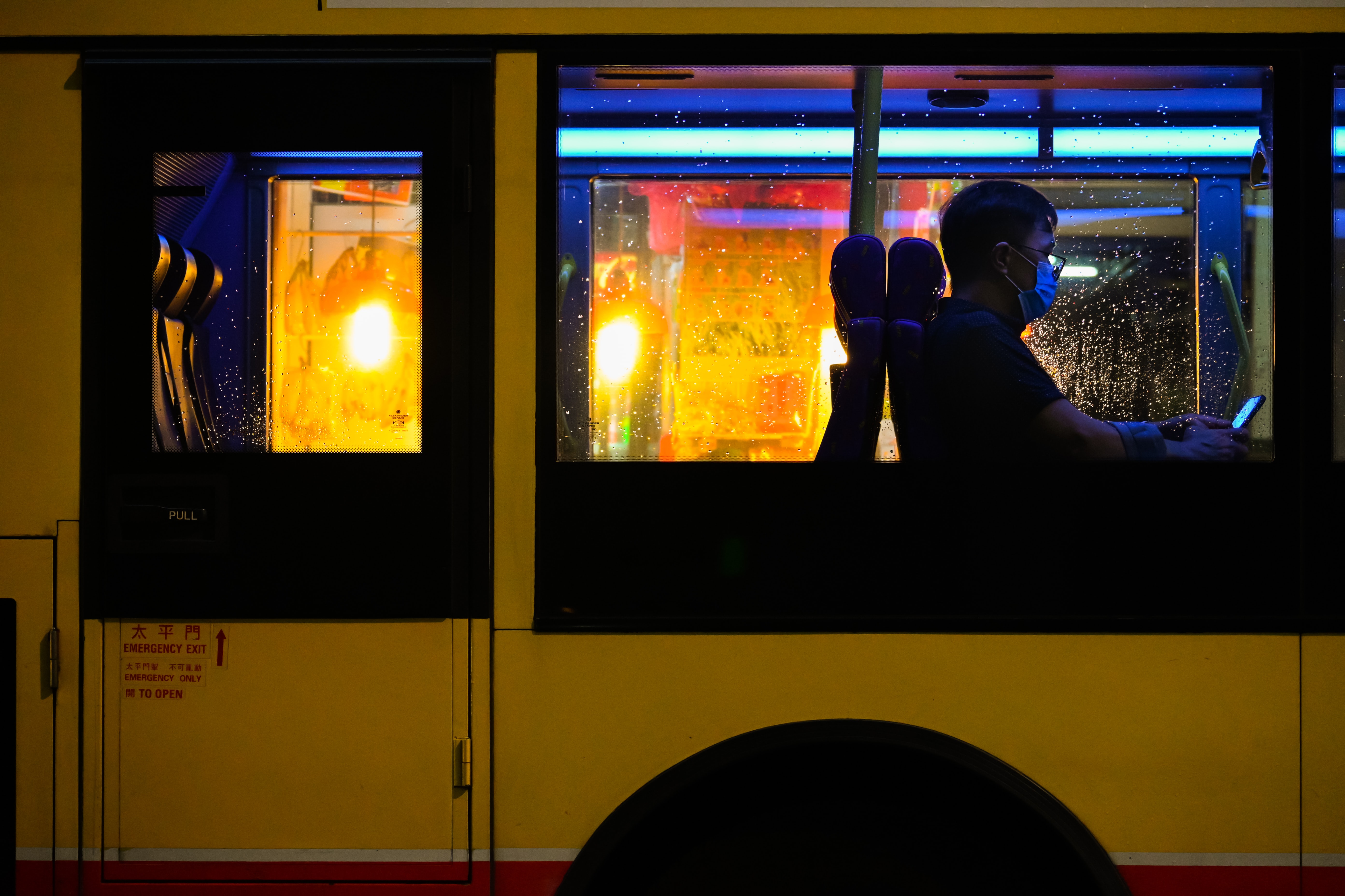 Man on bus at night; image by Drown in City, via Unsplash.com.