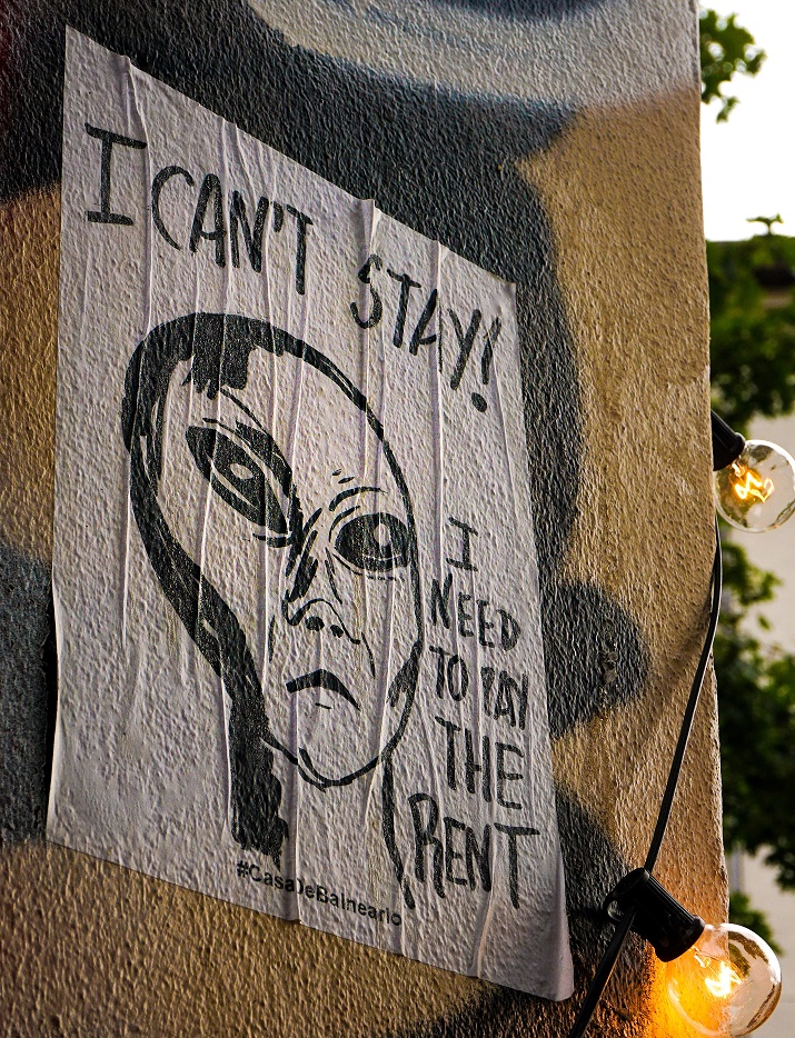 Street art drawing of an iconic alien face, with a caption that reads, "I can't stay, I need to pay the rent."