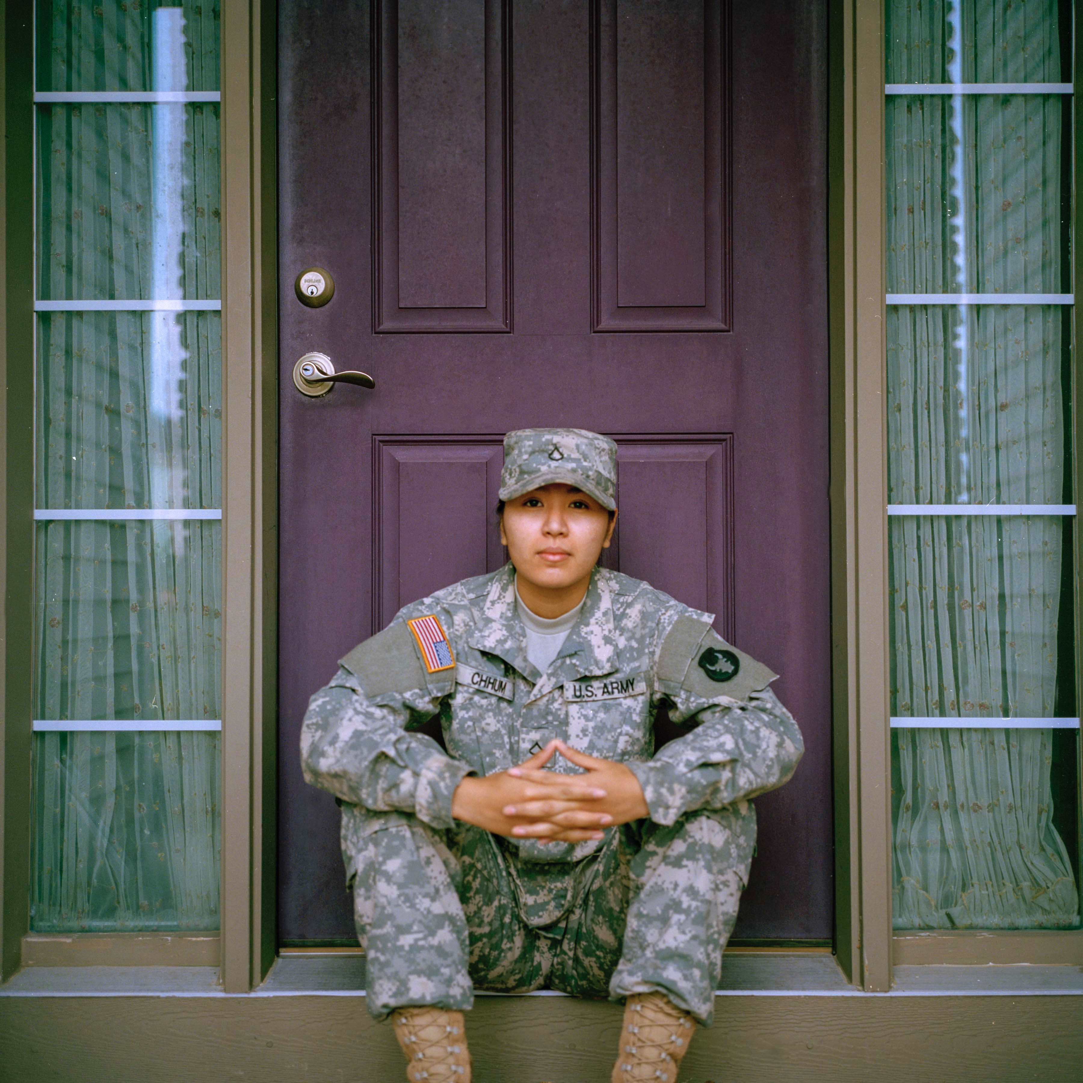 Female service member in uniform sitting on porch step in front of door; image by Jessica Radanavong, via Unsplash.com.