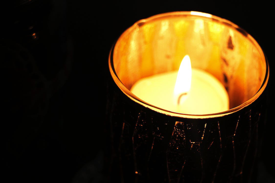 A single votive candle lights the darkness.
