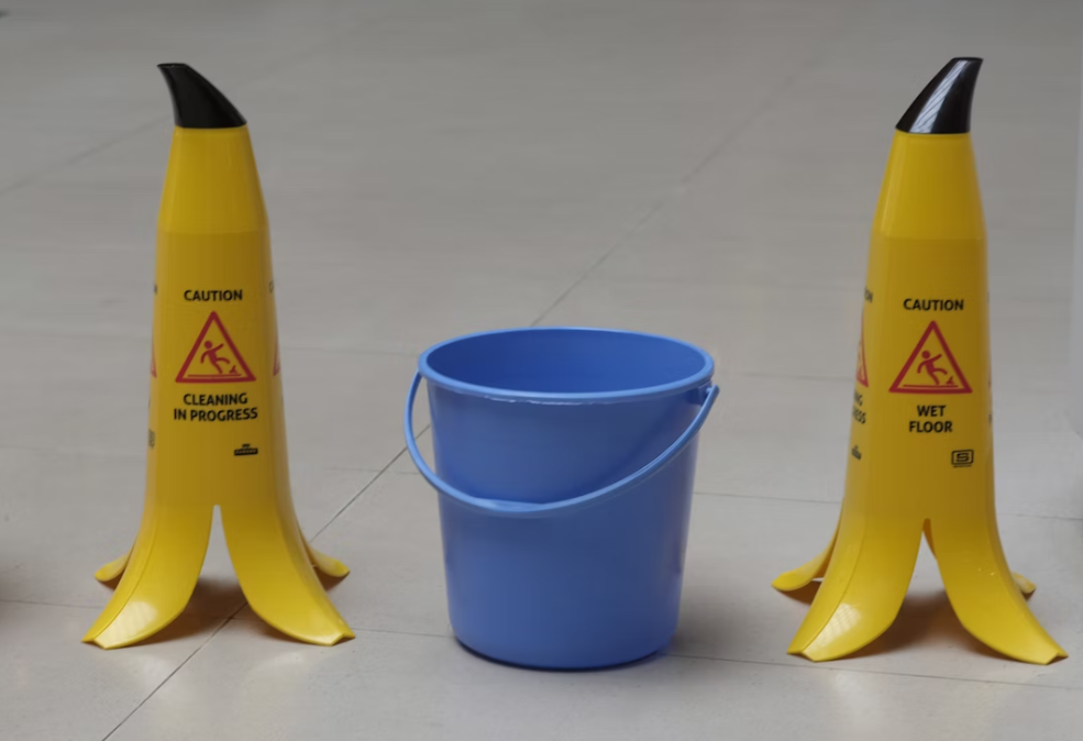 Banana-shaped caution signs on either side of a blue bucket; image by Galen Crout, via Unsplash.com.