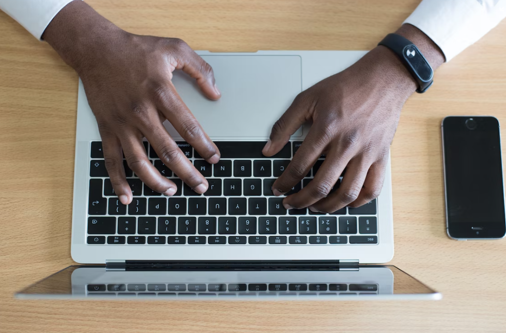 Black man's hands and laptop keyboard; image by Cytonn Photography, via Unsplash.com.