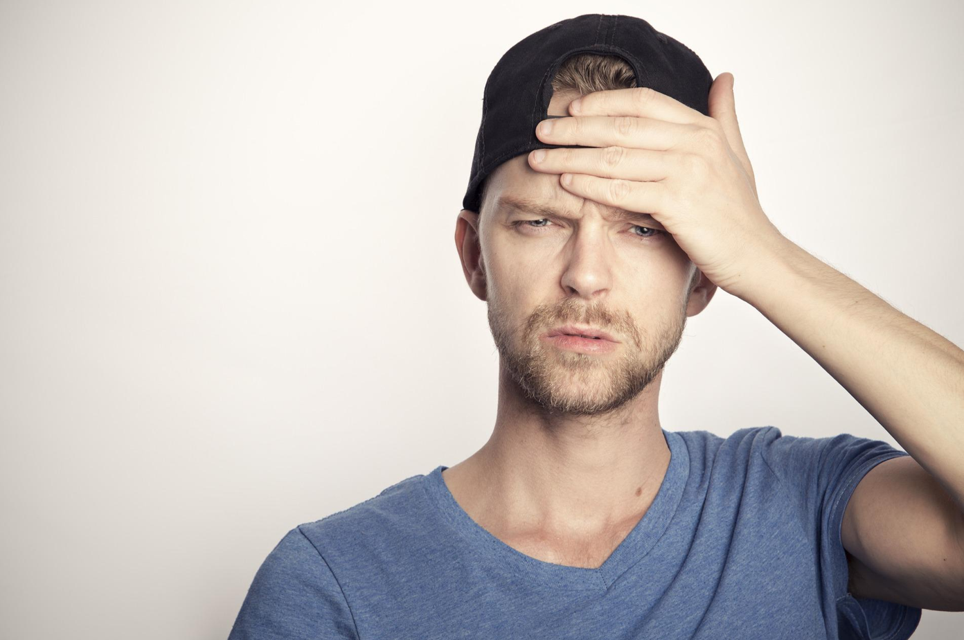Man in t-shirt with backward ball cap and hand on forehead; image by 10634669, via Pixabay.com.