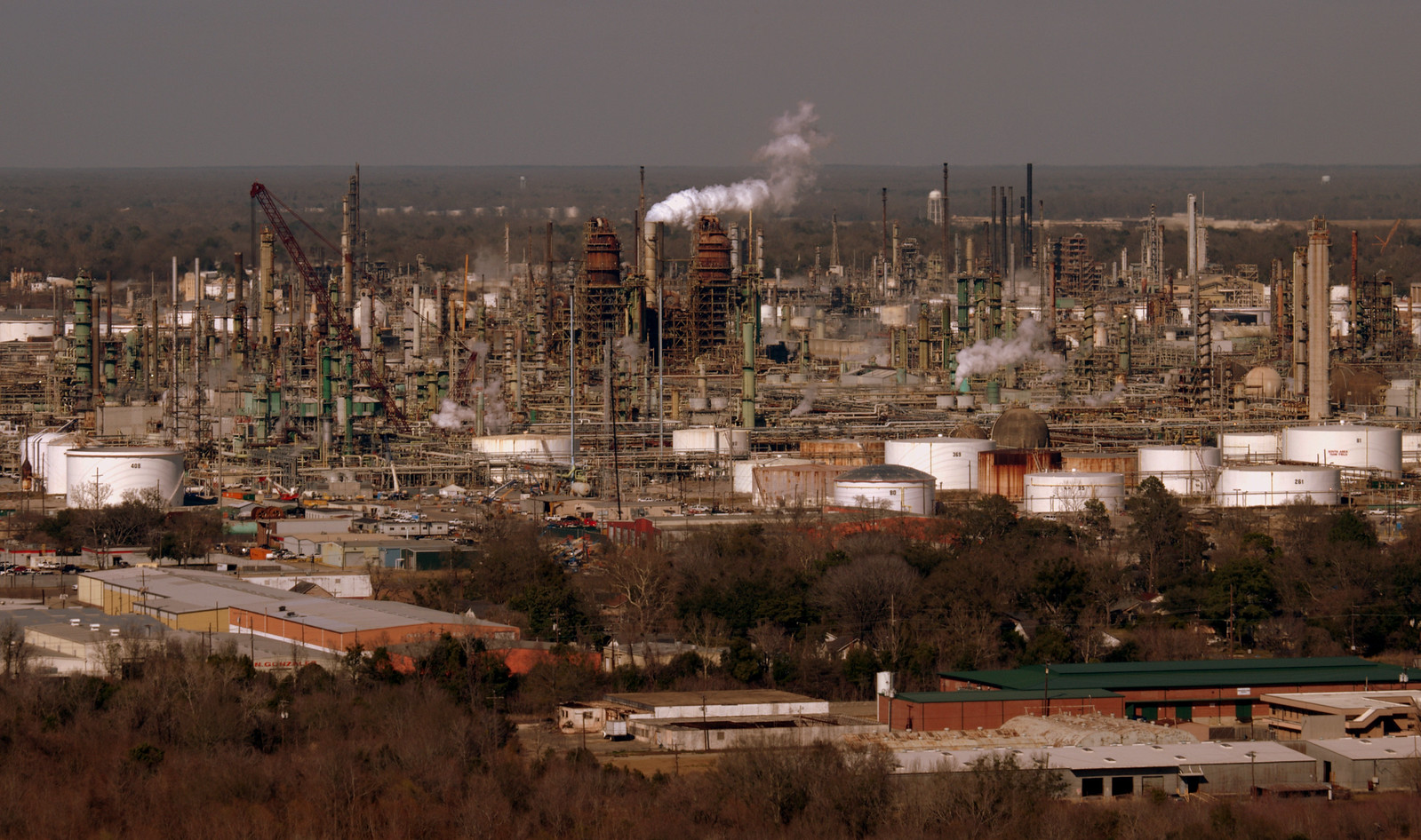 A landscape covered by oil and gas refining infrastructure, such as large holding tanks, smokestacks and a variety of towers.