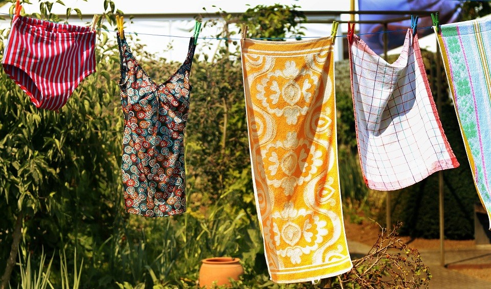 A clothesline, from which hangs towels, a bathing suit, and swim trunks.
