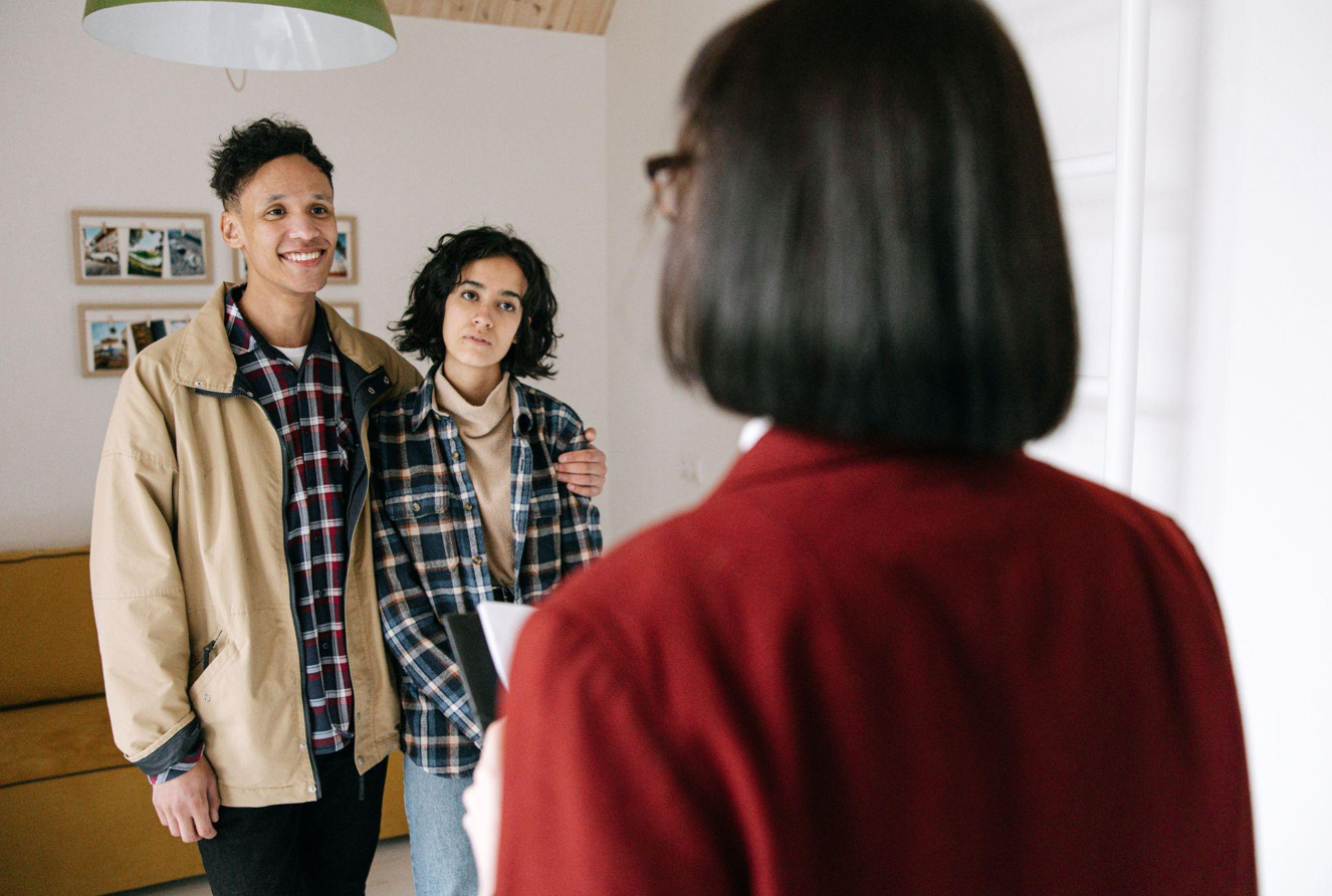 Couple standing in front of real estate agent; image by Ivan Samkov, via Pexels.com.