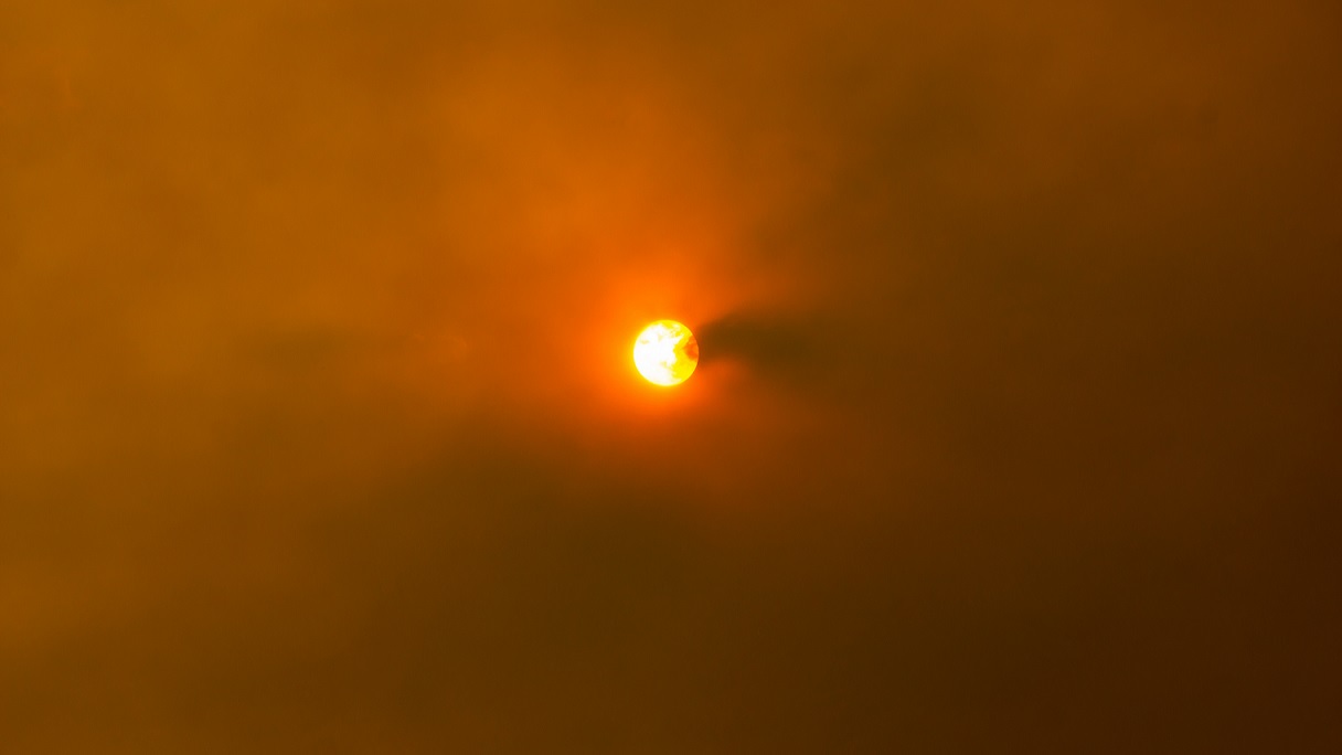 The sun, much obscured by a sky filled with smoke from wildfires.