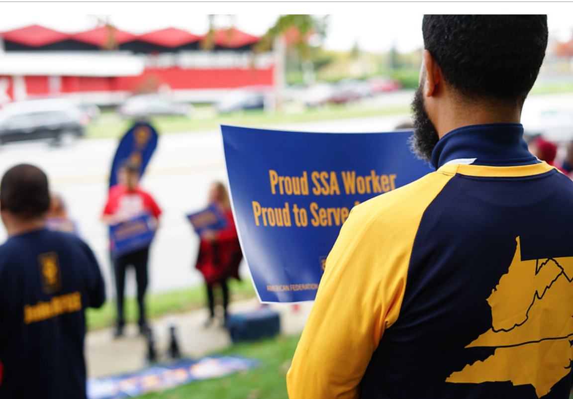 Man holding sign that says "Proud SSA Worker" at rally; image courtesy of AFGE.