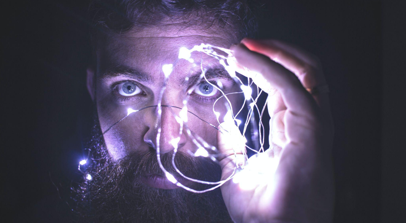 Man holding string of lights; image by David Cassolato, via Pexels.com