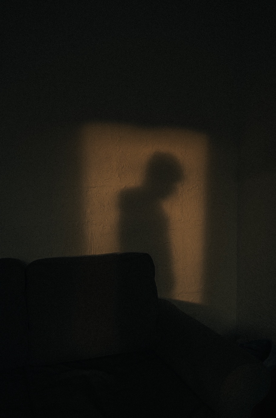 Shadow of a boy in a lit doorway; image by Majestic Lukas, via Unsplash.com.