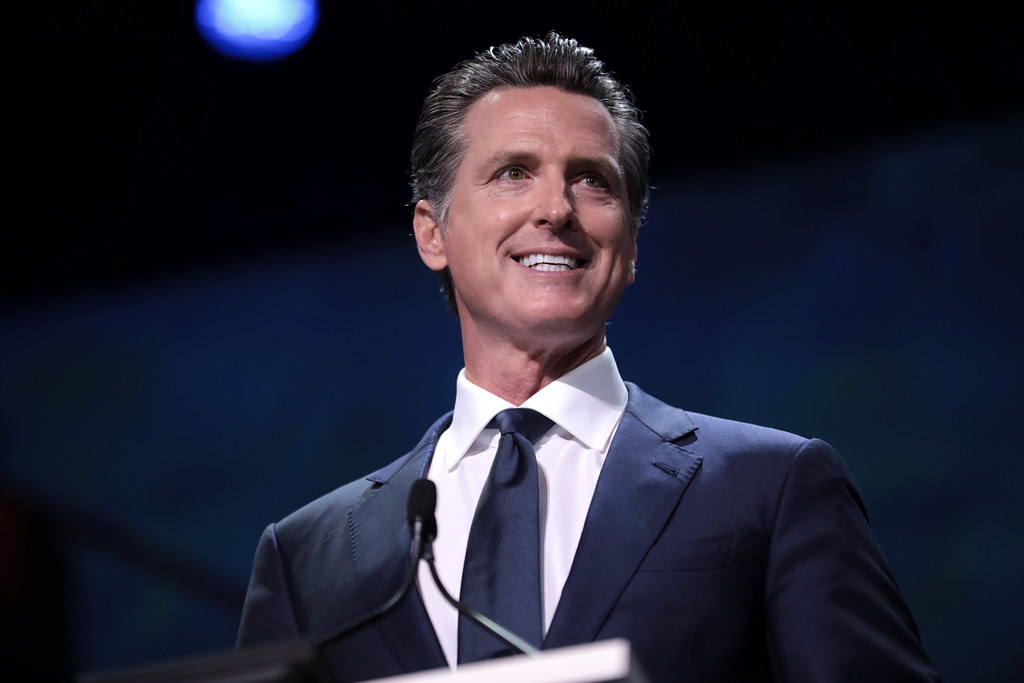 A smiling man in a suit and tie standing at a podium.