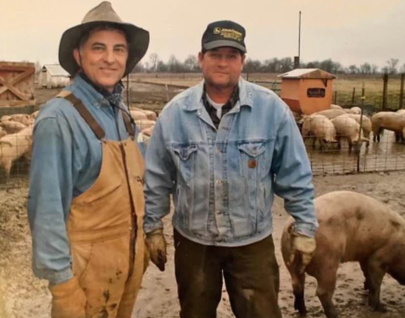 Two hog farmers with hogs; image courtesy of press release.