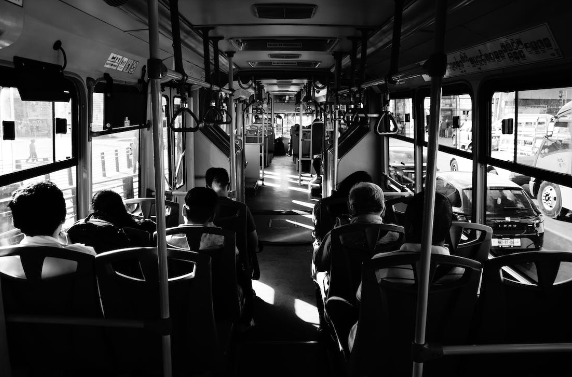 Grayscale image of people inside a bus; image by Steve Aksnes, via Pexels.com.