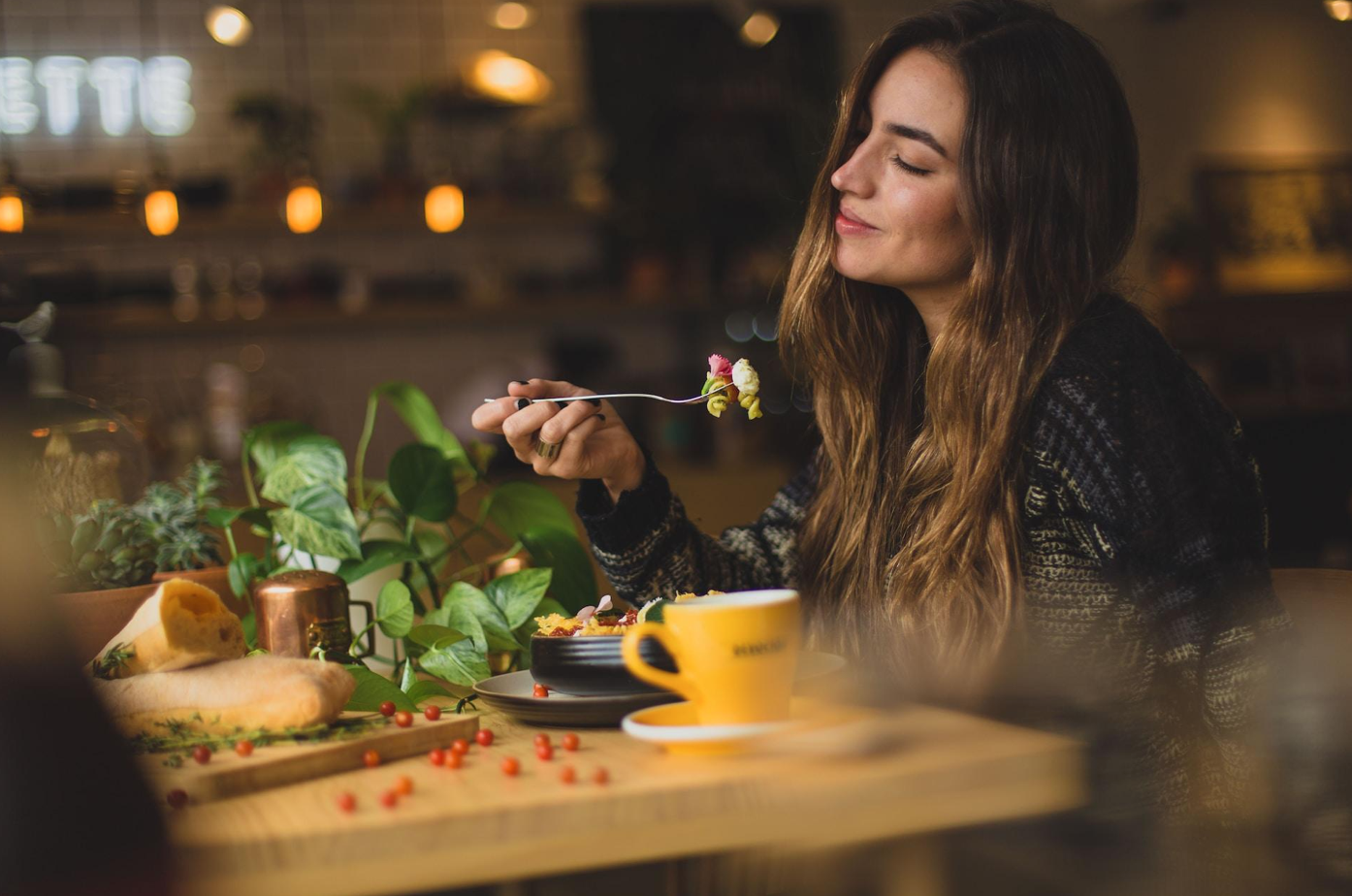 Woman at table holding fork; image by Pablo Merchán Montes, via Unsplash.com.