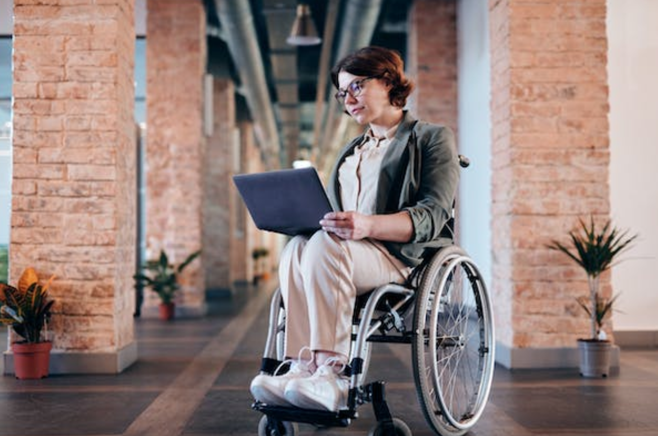 Woman in wheelchair with laptop; image by Marcus Aurelius, via Pexels.com