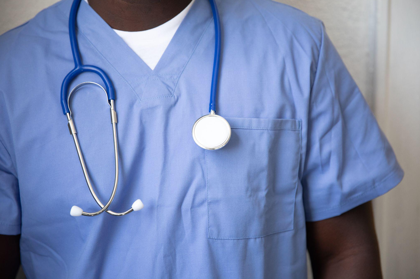 Black man in blue scrubs with stethoscope around his neck; image by Nappy, via Unsplash.com.