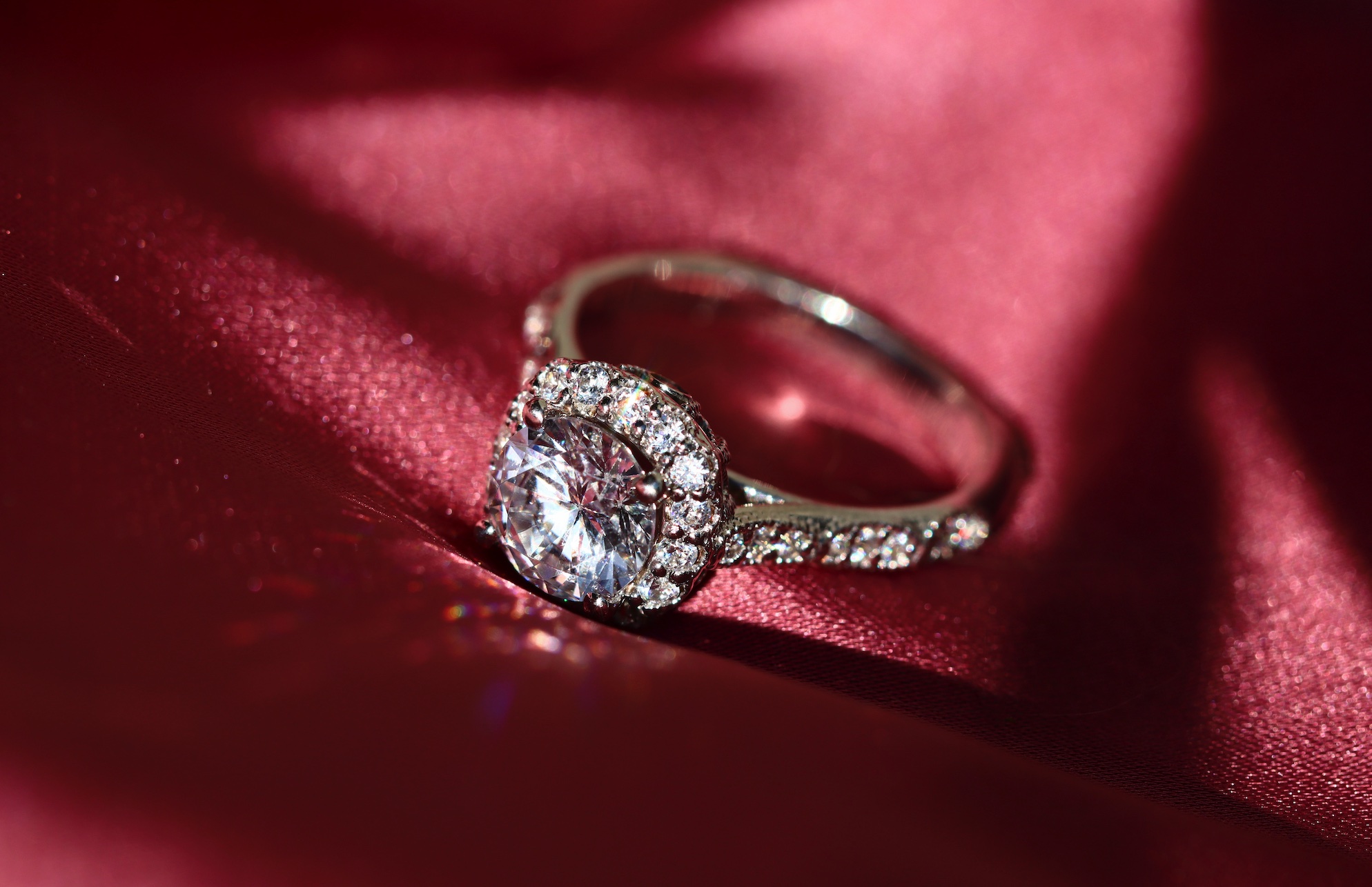 Diamond ring on red fabric background; image by Sabrianna, via Unsplash.com.