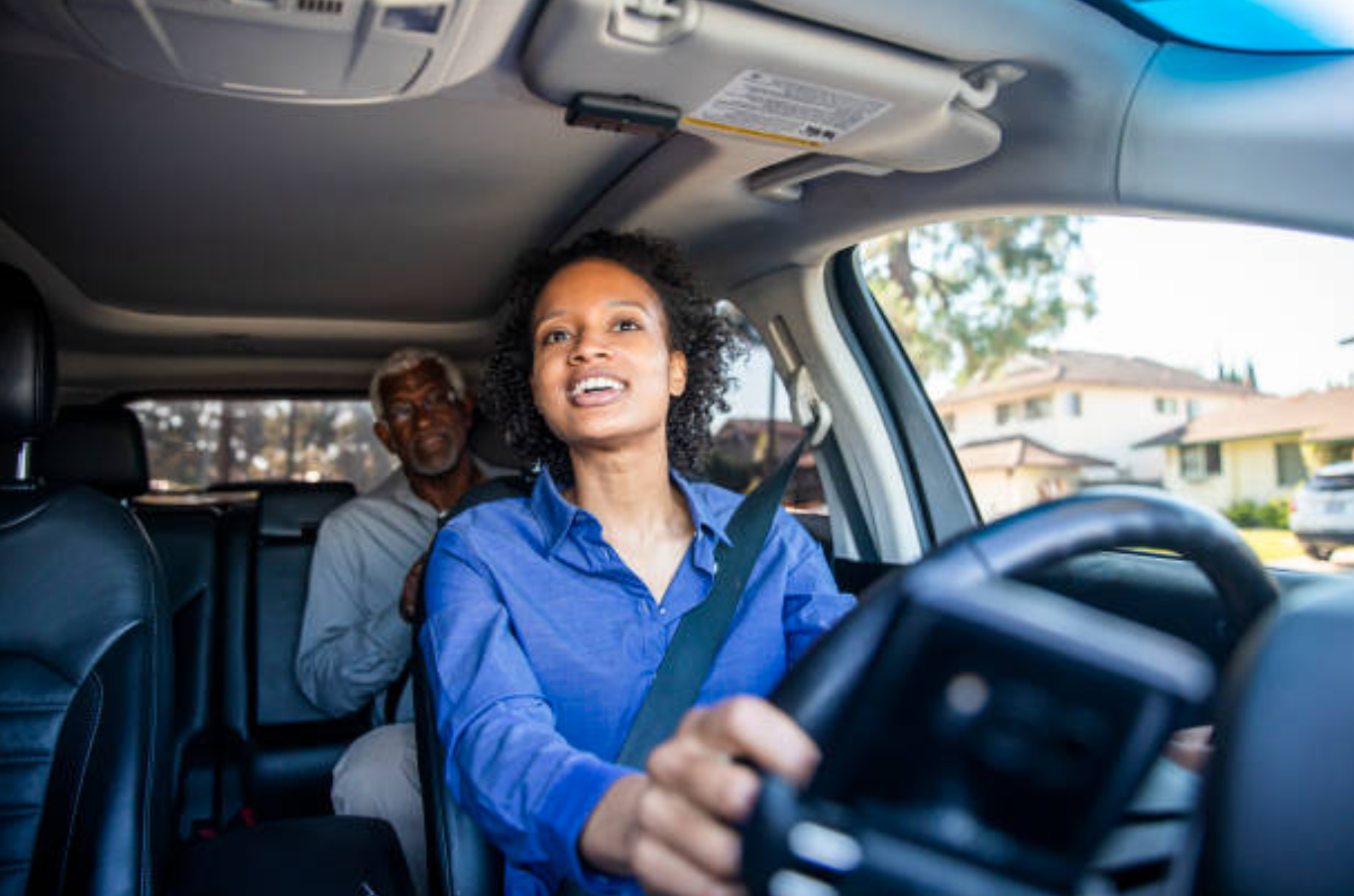 A young black woman drives a passenger in her car as a professional driver; image by adamkaz, via iStockphoto.com.
