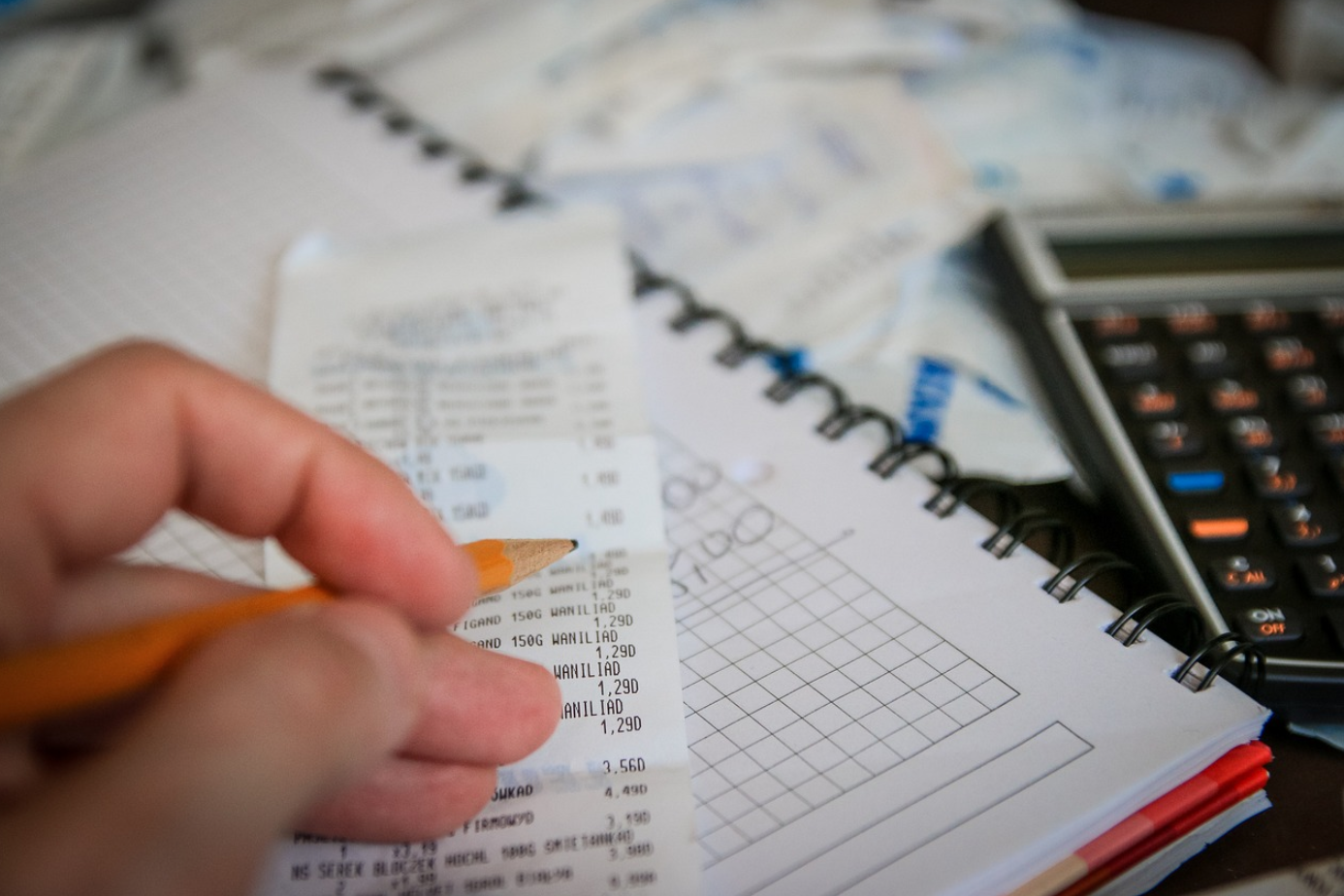 Calculator, receipt, notebook near person with pencil; image by Jarmoluk, via Pixabay.com.