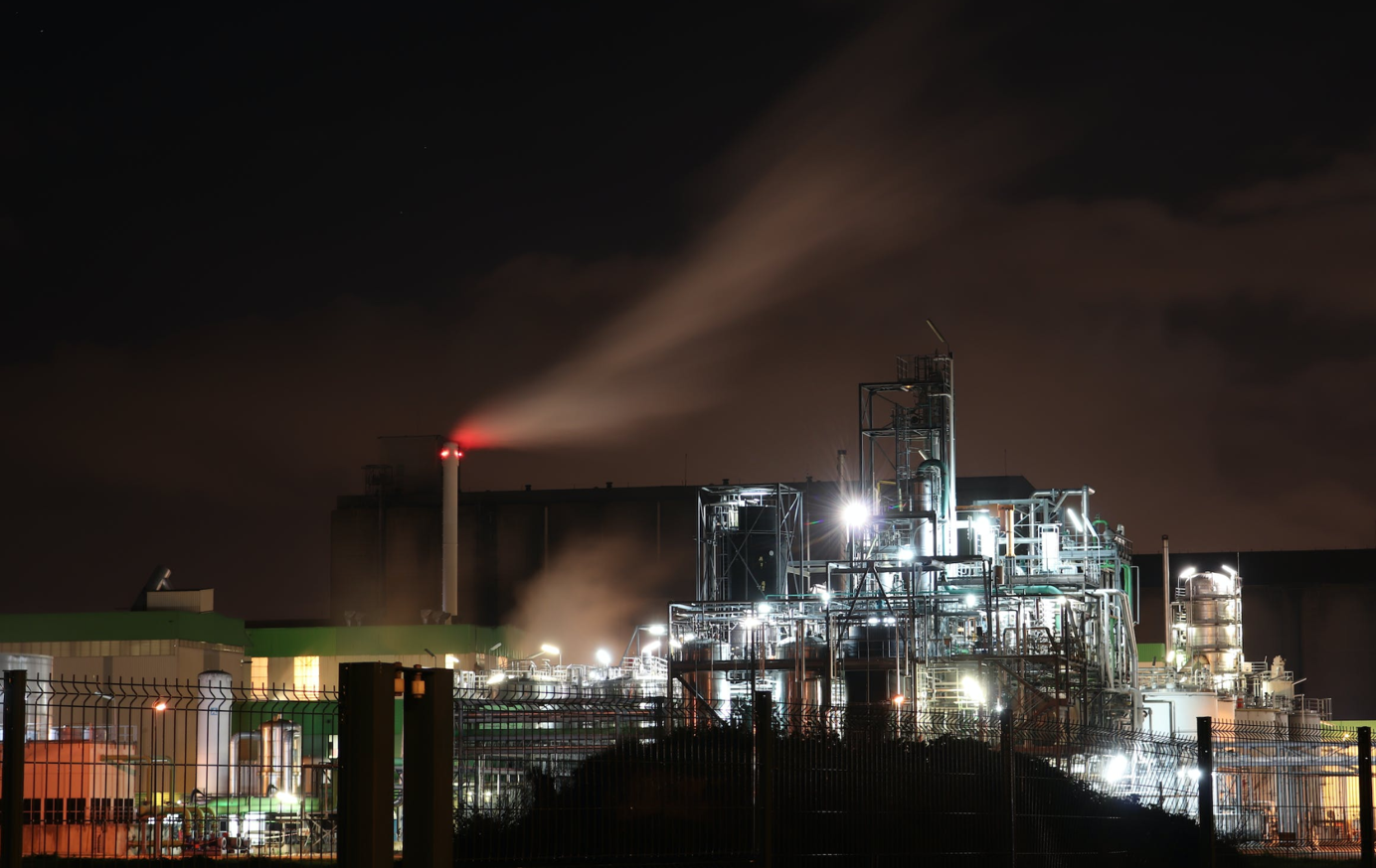 Industrial building at night; image by Loïc Manegarium, via Pexels.com.