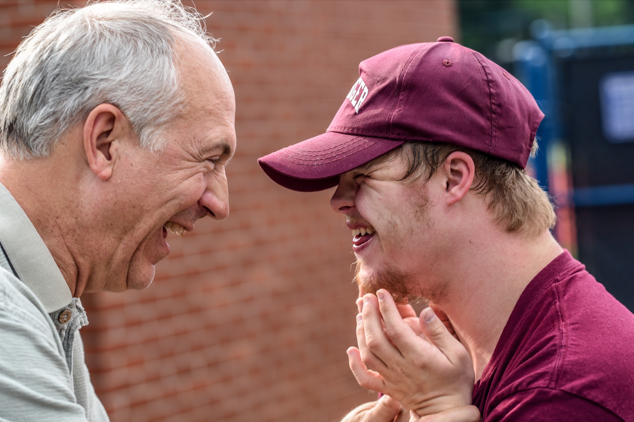 Moment of laughter between older man and younger man with Down Syndrome; image by Nathan Anderson, via Unsplash.com.