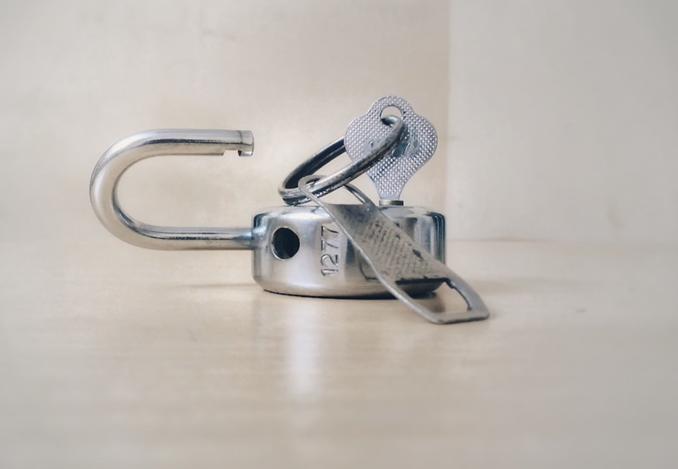Open padlock with key; image by Basil James, via Unsplash.com.