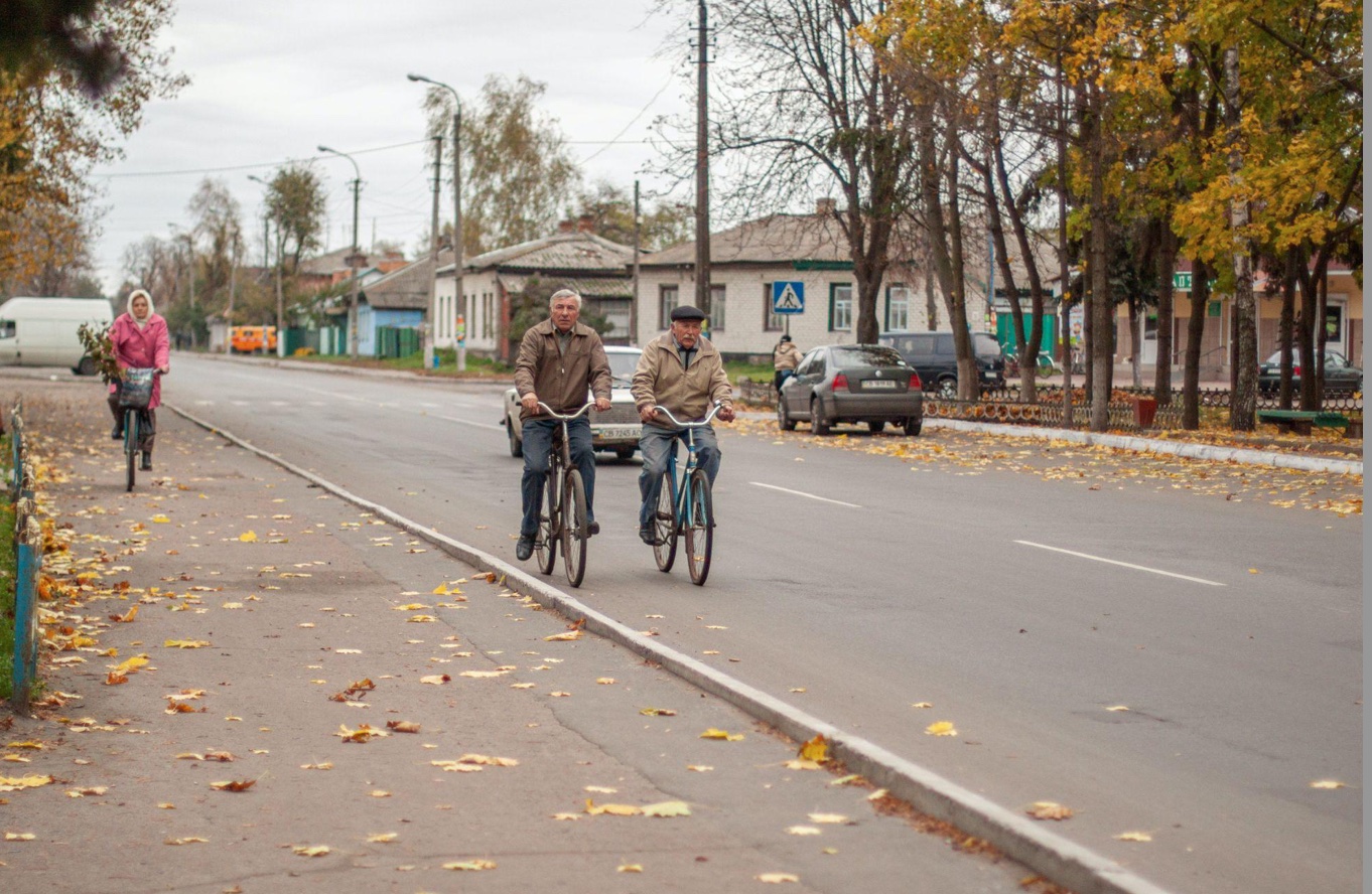 Three older people riding bikes down the street in autumn; image by Nadiia Yahaha, via Pexels.com.