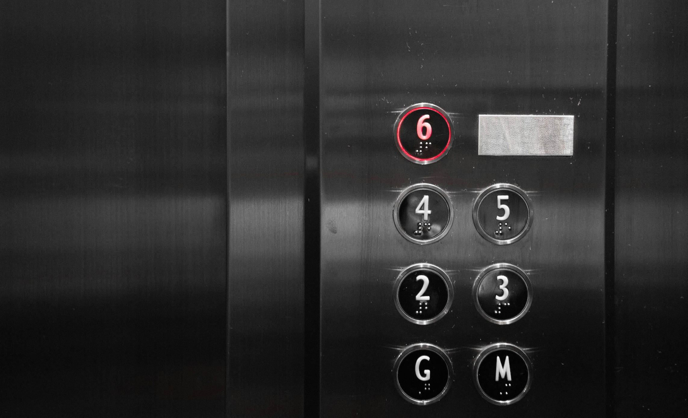 Metal elevator wall with buttons, number six lit up in red; image by Arisa Chattasa, via Unsplash.com.